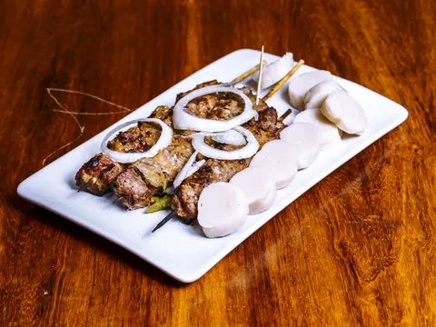 Grilled skewers with onion and cassava on a white plate