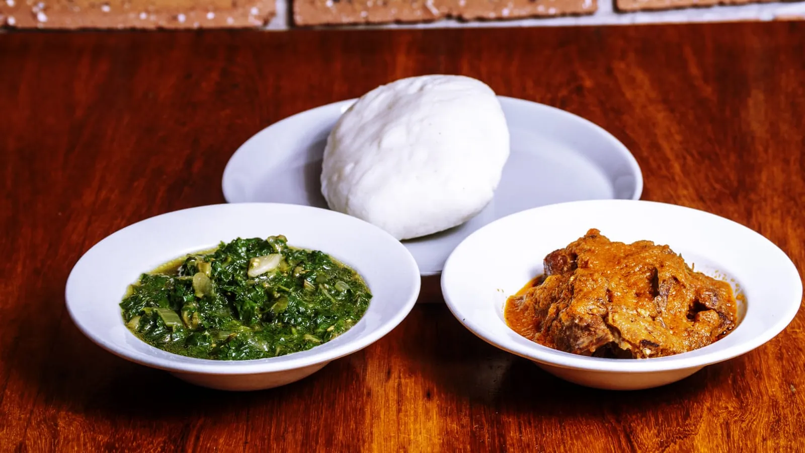 A plate of pap, greens and stew ready at the table